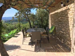 een tafel en stoelen op een patio met een stenen muur bij Mas De Gordes in Gordes