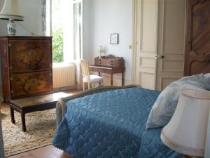 a bedroom with a bed and a desk and a window at Château Fontclaire in Pons