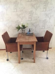 een houten tafel en twee stoelen met bloemen erop bij B&B De Koraal in Emmen