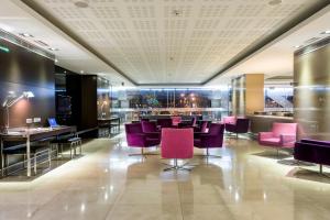 a restaurant with purple chairs and a bar at Hotel Zenit Pamplona in Cordovilla