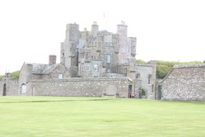 an old castle with a grass field in front of it at Harbour House Bed & Breakfast - Wick in Wick