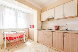 una cocina con armarios de madera, mesa y sillas en ARTAL Apartment on Obolonskyi Avenue 16a, en Kiev
