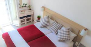 łóżko z czerwono-białym kocem i poduszkami w obiekcie Sappho Plomari w mieście Plomari