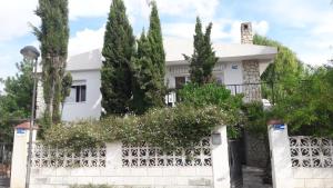 a white house with trees behind a white fence at Chalet Maria con Jardín Mediterráneo in San Juan de Alicante