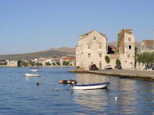 deux bateaux dans l'eau à côté d'un vieux bâtiment dans l'établissement Apartments Dalmatino, à Kaštela