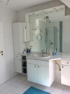 Baño blanco con lavabo y espejo en Schöne Zimmer im Zentrum Leben en Offenburg