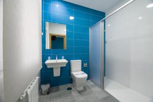Baño de azulejos azules con aseo y lavamanos en A Chousa, en Arzúa