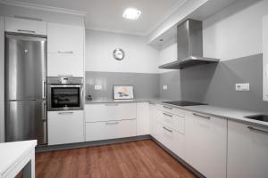 a kitchen with white cabinets and a stainless steel refrigerator at Vivienda O Pombal in Cambados