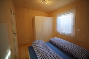 FlühliにあるChalet Nr. 50のベッド2台、冷蔵庫、窓が備わる客室です。