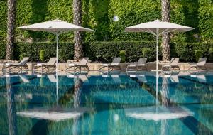 una piscina con sedie e ombrelloni di Hotel Yehuda a Gerusalemme
