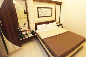 a small bedroom with a bed and a mirror at Hotel Al Moazin in Mumbai