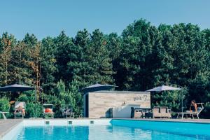 una piscina en un complejo con mesas y sombrillas en Park7 en Tiszafüred