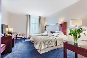 a hotel room with two beds and a desk at Hotel Atrium in Szczecin