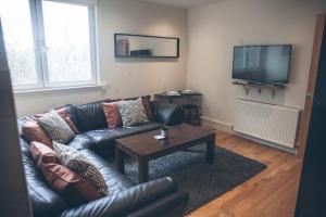a living room with a leather couch and a tv at Apartment E in Aberdeen