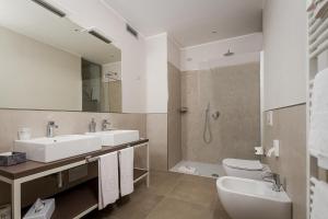 een badkamer met 2 wastafels, een toilet en een douche bij Hotel Griso Collection in Malgrate