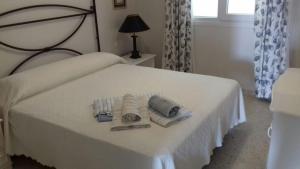 Un dormitorio con una cama blanca con toallas. en Los Lances Pastor, en Tarifa