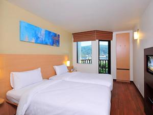 a bedroom with two white beds and a television at Ibis Phuket Kata in Kata Beach