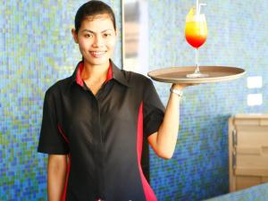 a woman holding a tray with a drink on it at Ibis Phuket Kata in Kata Beach