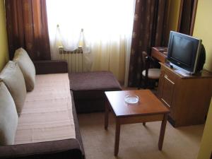 sala de estar con sofá, TV y mesa en Hotel Vila Sunce, en Stara Pazova