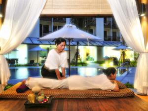 a woman giving a boy a massage in front of a pool at Ibis Phuket Kata in Kata Beach