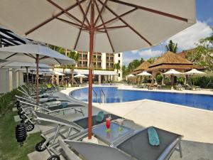 a pool with chairs and umbrellas next to a resort at Ibis Phuket Kata in Kata Beach
