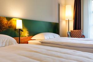 a hotel room with two beds and a window at Hotel Bellinzona Sud Swiss Quality in Monte Carasso