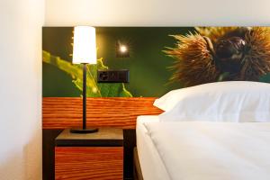 a bedroom with a bed and a lamp on a table at Hotel Bellinzona Sud Swiss Quality in Monte Carasso