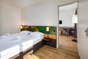 a bedroom with a large white bed and a mirror at Hotel Bellinzona Sud Swiss Quality in Monte Carasso