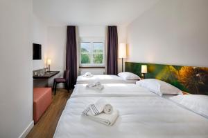 a hotel room with four beds with towels on them at Hotel Bellinzona Sud Swiss Quality in Monte Carasso
