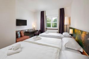 a hotel room with two beds and a window at Hotel Bellinzona Sud Swiss Quality in Monte Carasso