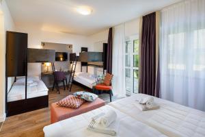 Habitación de hotel con 2 camas y sala de estar. en Hotel Bellinzona Sud Swiss Quality en Monte Carasso