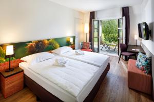a bedroom with a large white bed and a living room at Hotel Bellinzona Sud Swiss Quality in Monte Carasso