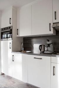 uma cozinha branca com armários e electrodomésticos brancos em Haags Duinhuis - familyfriendly holidayhome em Haia