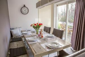 a dining room table with flowers and a clock on the wall at Haags Duinhuis - familyfriendly holidayhome in The Hague