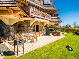 a house with a patio with a table and chairs at TatryTop Panorama Lux Spa in Kościelisko