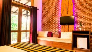 a bedroom with a bed and a brick wall at Roshara Nalla in Giriulla