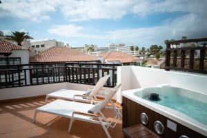 a balcony with a hot tub and chairs on a roof at Vanilla Garden Boutique Hotel - Adults Only in Playa de las Americas