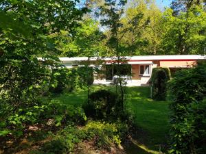 una casa en medio de un patio con árboles en Knusse 5 Persoons Bungalow Hartje Veluwe en Otterlo