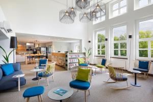 a waiting room with chairs and tables and a library at Hotel Bellinzona Sud Swiss Quality in Monte Carasso