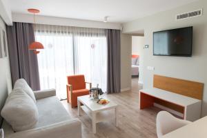 a living room with a couch and a tv at Vanilla Garden Boutique Hotel - Adults Only in Playa de las Americas