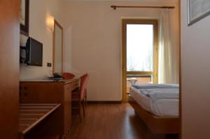 a bedroom with a bed and a desk and a window at Parc Hotel Casa Mia in Lazise