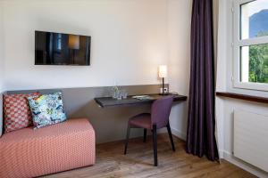 a room with a table and a chair and a desk at Hotel Bellinzona Sud Swiss Quality in Monte Carasso