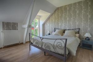 - une chambre avec un lit et un mur dans l'établissement Au Jardin Fleuri, à Vauxaillon