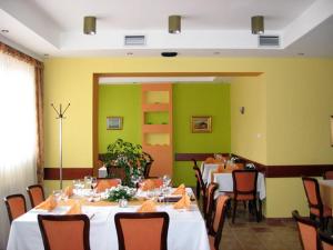 ein Esszimmer mit Tischen und Stühlen und grünen Wänden in der Unterkunft Hotel Vila Sunce in Stara Pazova