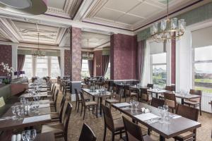 un comedor con mesas, sillas y ventanas en The Grand Atlantic Hotel, en Weston-super-Mare