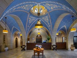 a lobby with a blue and white ceiling with flowers on a table at YMCA Three Arches Hotel in Jerusalem