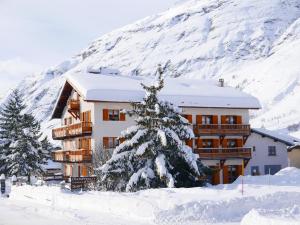 a building in the snow with a tree in front of it at Chez Mamie Anna (B&B et Chalet) in Bessans