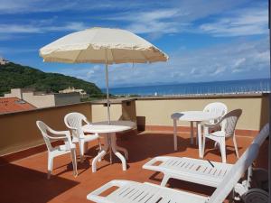 a patio with tables and chairs and an umbrella at Residence I Boboli BC in Punta Ala