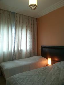 a bedroom with two beds and a lamp and a window at Perle de Tamaris in Dar Bouazza