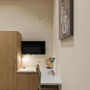 Habitación con escritorio y TV en la pared. en B&B De Windheer, en Sint-Martens-Lennik